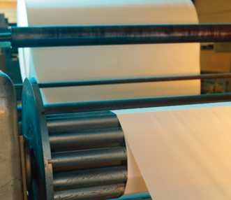 Industriële machine met rollen die papier nauwkeurig doorvoeren voor het stansen van maatvaste onderdelen.