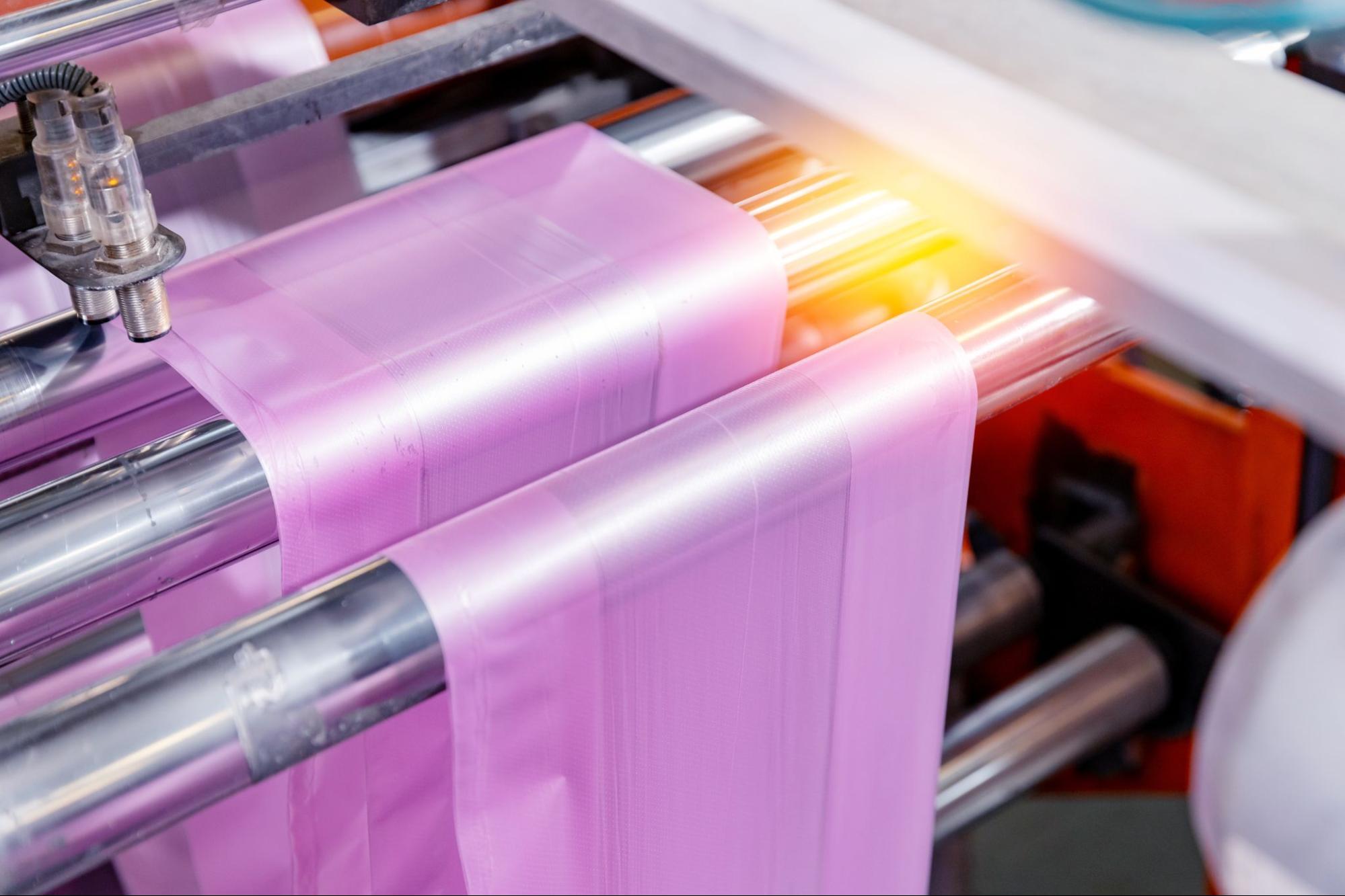Roze kunststoffolie die door een industriële stansmachine wordt geleid voor precisiebewerking.